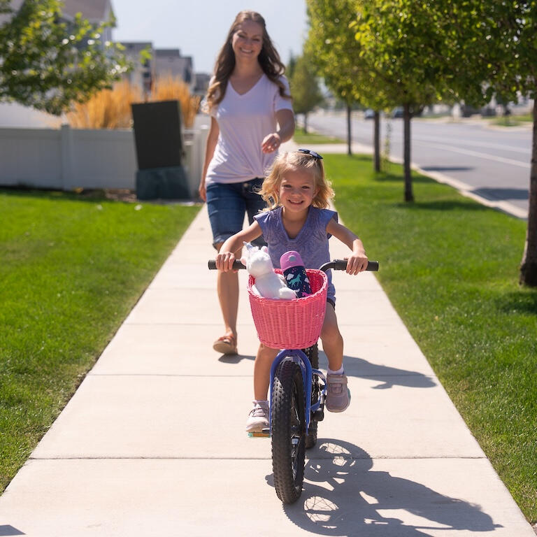 Mother accompanies daughter riding her bike with the innovative Pedalon bike basket for girls.