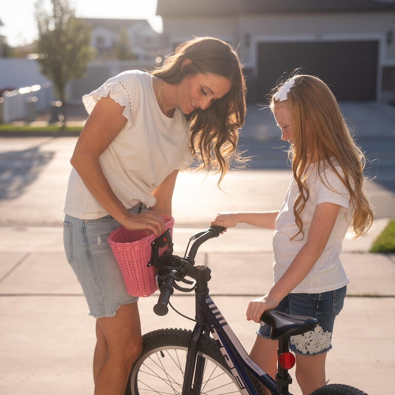 Mother helps daughter attach the innovative Pedalon bike basket for girls.